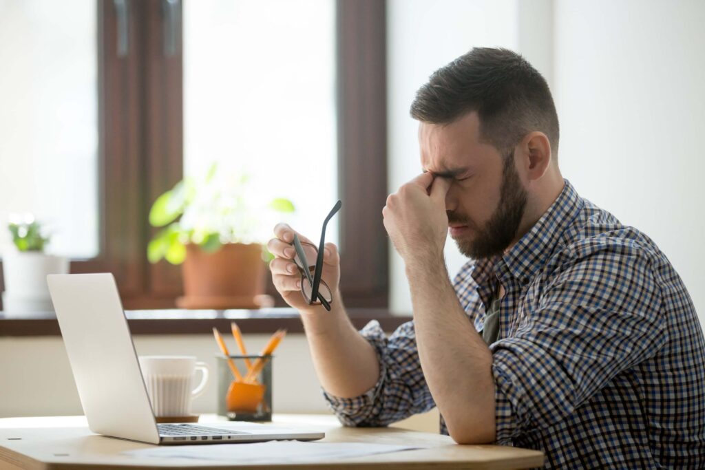 Man Suffering from eye strain caused by prolonged screen time